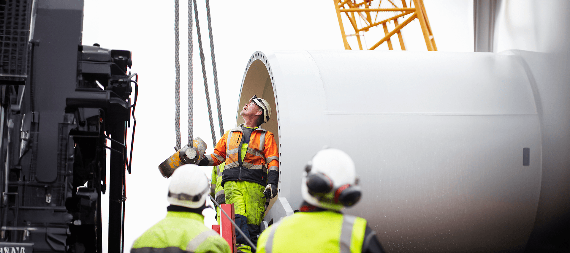 Field technicians in high-visibility gear working a wind turbine component on site