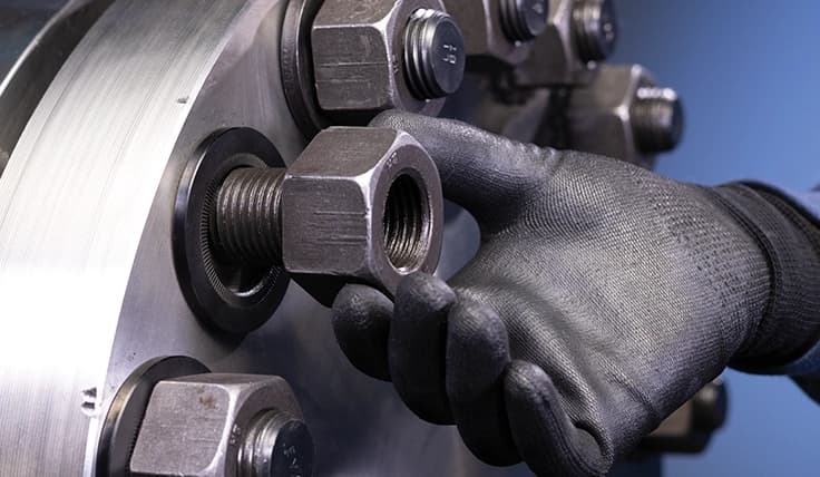 A gloved hand threading a nut onto a bolt with a TRUE-LOCK Washer already installed